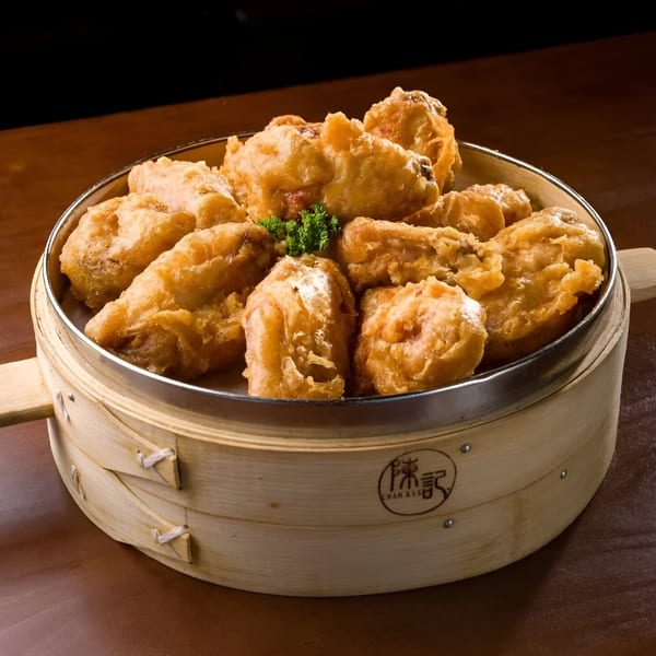Golden-fried chicken pieces, garnished with parsley, served in a traditional Chan Kee bamboo steamer.