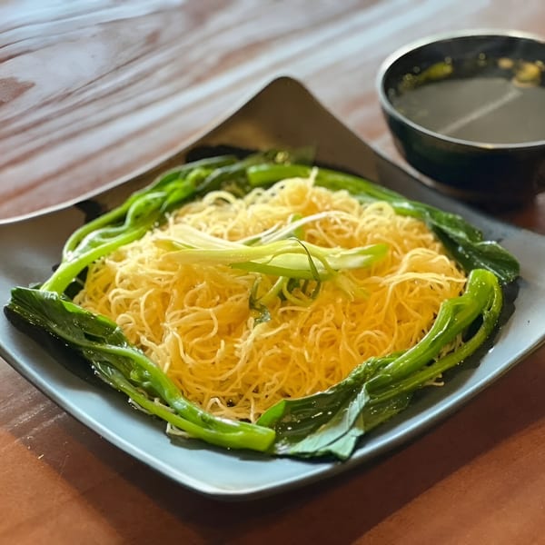 Chan Kee's Chinese noodles with green vegetables and scallions, served with a side of soup.